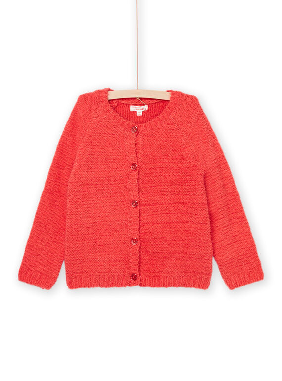 Une jeune fille souriante portant un cardigan court rouge Du Pareil au Même par-dessus une robe à motifs